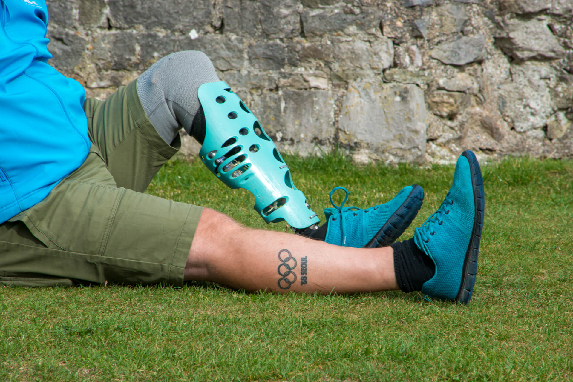 Man sit on grass wearing turquoise leg cover